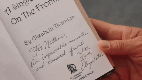 a person is holding a book that has a signature on it