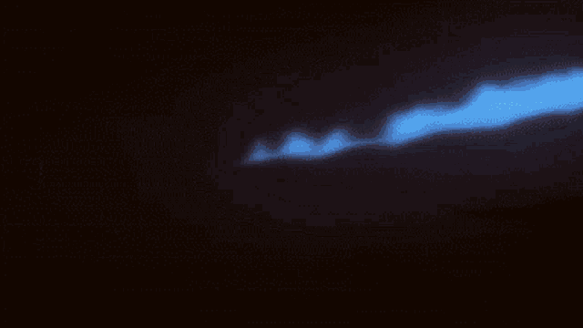 a blue flame is coming out of a black background