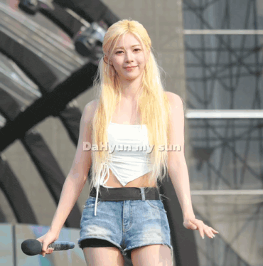 a woman in a white tank top and denim shorts is holding a microphone and the name dahyun my sun is on the bottom right