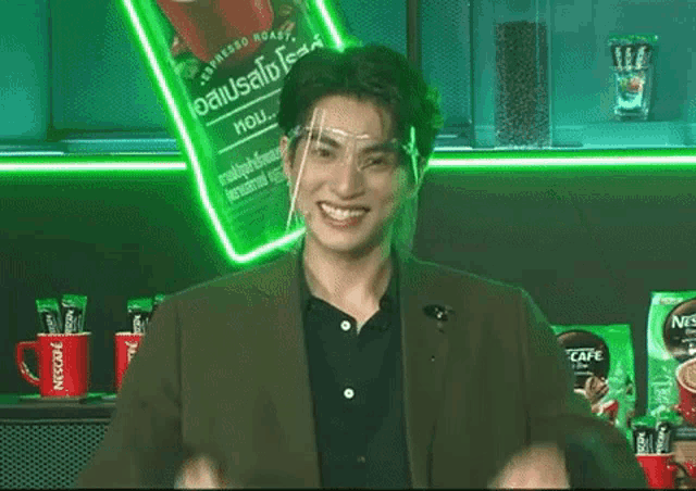 a man wearing a face shield and a suit is standing in front of a neon sign .