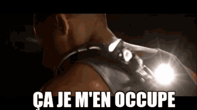 a man is wearing a flashlight on his back and the words `` ca je m 'en occupe '' are written on the screen .