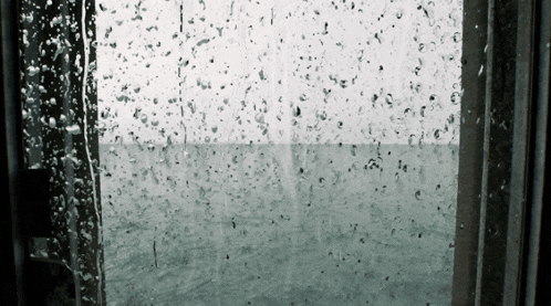 a window with rain drops on it and a view of a body of water