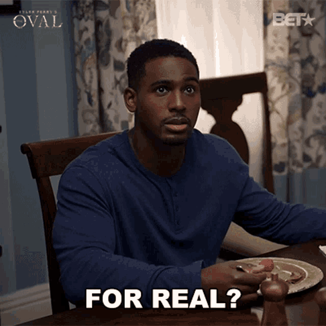 a man in a blue shirt is sitting at a table with a plate of food and the words for real written on the bottom