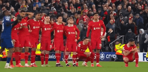 a soccer team is kneeling down on the field during a game .