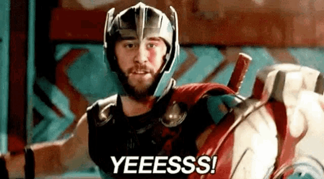 a man in a superhero costume is holding a shield and saying yeeess .