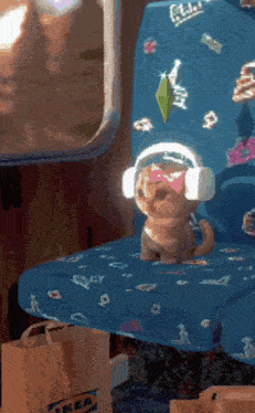 a cat wearing headphones and a bow sits on a blue seat