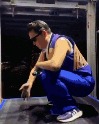 a man in blue overalls squatting on a table
