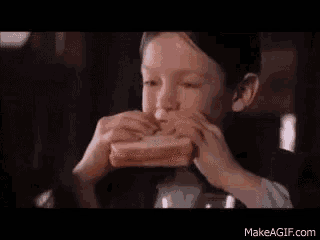 a young boy is eating a sandwich with peanut butter and jelly .