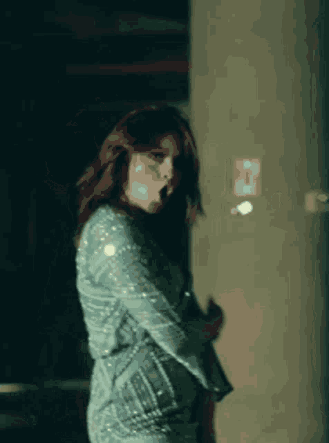 a woman in a blue sequined dress is dancing in front of a sign that says exit