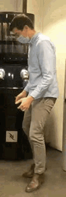 a man wearing a mask is standing in front of a coffee grinder .