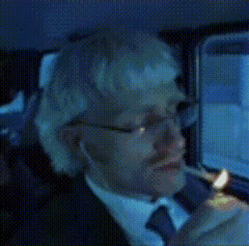 a man in a suit is smoking a cigarette in a car
