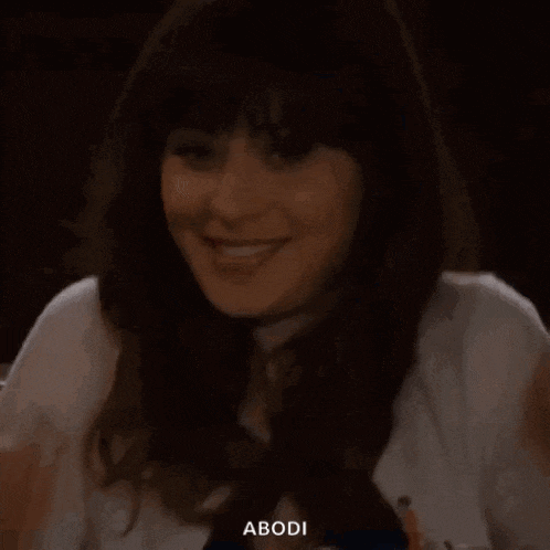 a woman is sitting at a table with her hand on her face and smiling .