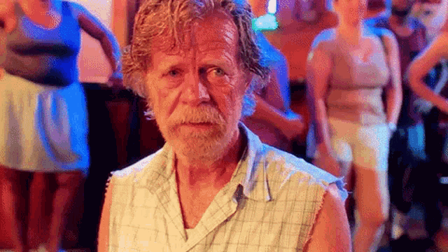 a man with a beard and a plaid shirt is standing in a crowd of people
