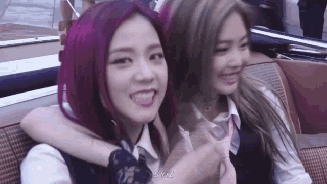a couple of girls with purple hair are sitting next to each other in a car .
