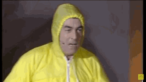 a man is wearing a yellow hooded jacket and a microphone .