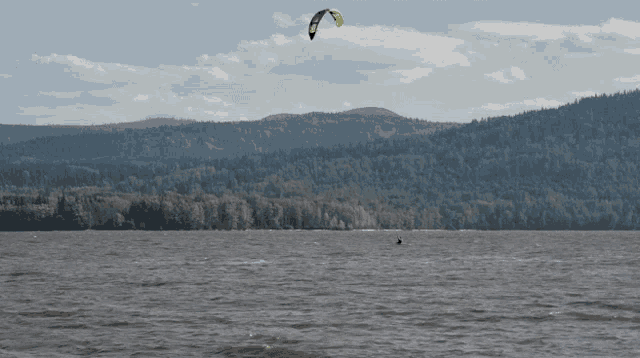 a person flying a kite over a body of water with mountains in the background