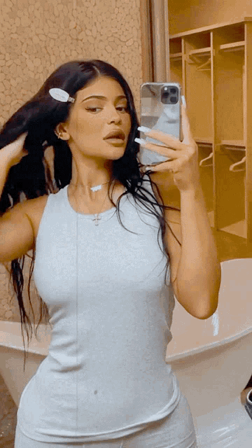 a woman taking a picture of herself in a bathroom mirror