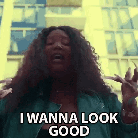 a woman is standing in front of a building and making a funny face while saying `` i wanna look good '' .