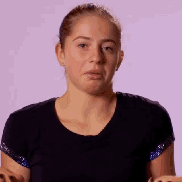 a woman wearing a black shirt with rhinestones on the sleeves is making a face