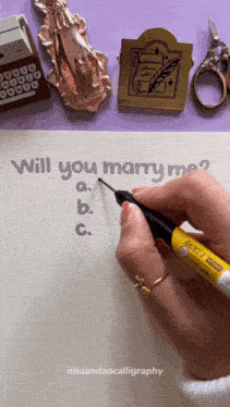 a person is writing the question will you marry me
