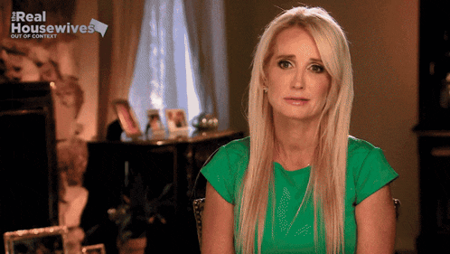 a woman in a green shirt is sitting in front of a sign that says real housewives out of context