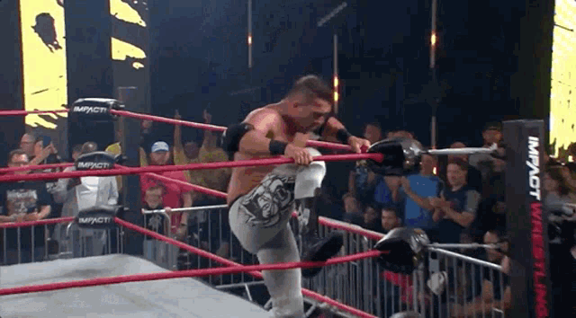 a man in a wrestling ring with a sign that says impact wrestling on it