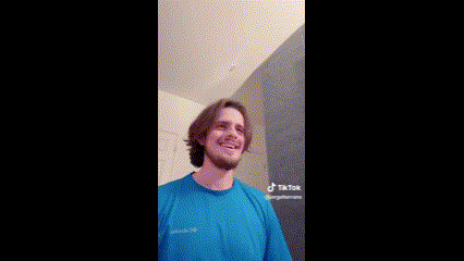 a man with a beard is wearing a blue shirt and smiling in a room .