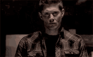 a close up of a man 's face with a plaid shirt on .