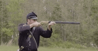 a man in a military uniform is holding a rifle in a field .