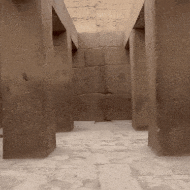 a narrow hallway with a brick wall and columns