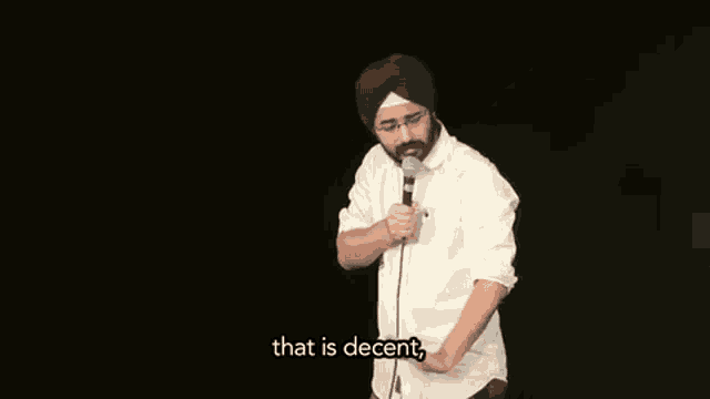 a man in a turban is holding a microphone in front of a black background and saying `` that is decent '' .