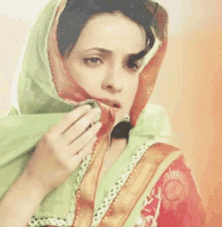 a woman covering her face with a green scarf and a necklace