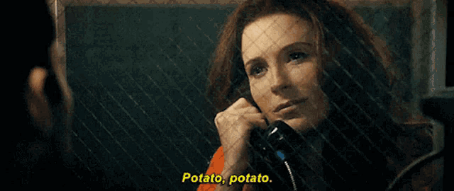 a woman is talking on a phone in a prison cell and says potato potato .