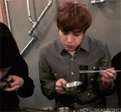 a man is sitting at a table eating with chopsticks and a bowl .