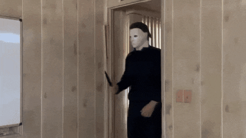 a man wearing a mask is holding a knife in a doorway