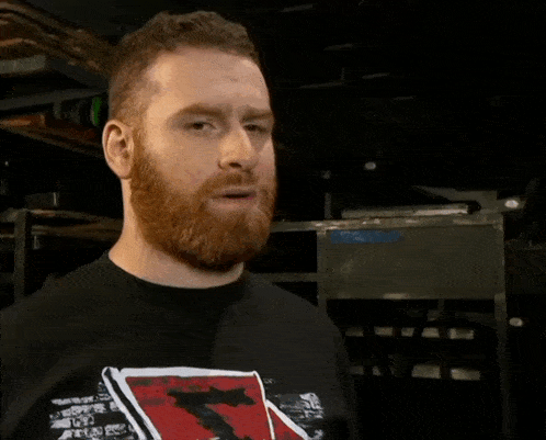 a man with a beard is wearing a black shirt with a skull and crossbones on it