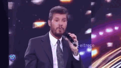 a man in a suit and tie singing into a microphone