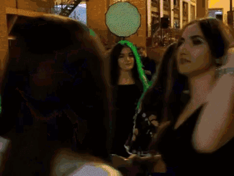 a woman in a black dress is standing in a crowd of people