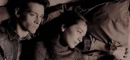 a man and a woman are laying on a couch holding hands .
