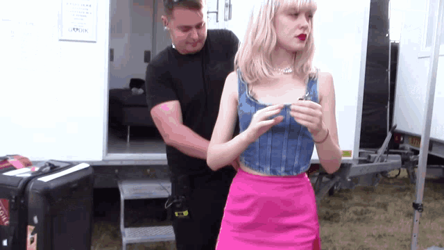 a woman wearing a pink skirt and a blue top is being helped by a man