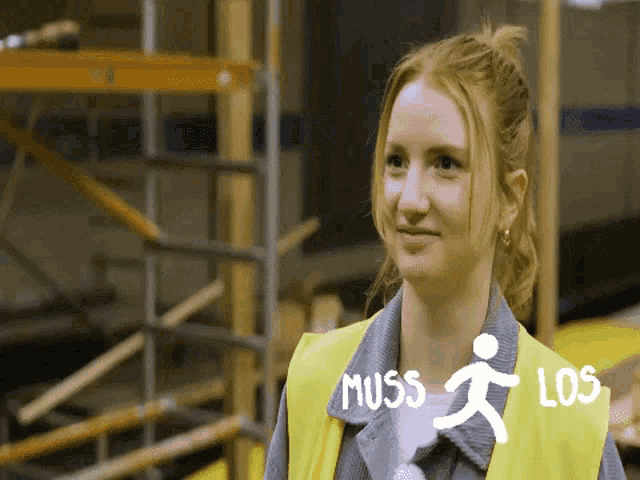 a woman wearing a yellow vest that says muss los on it