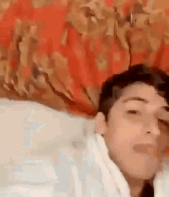 a man is laying on a bed with his eyes closed and a blanket on his head .