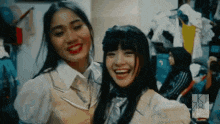 two young women are standing next to each other and smiling .