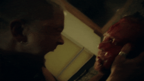 a man with a ring on his finger looks at a bloody face