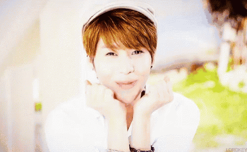 a woman wearing a white hat and a white shirt is smiling with her hands on her face .