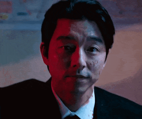 a man in a suit and tie is looking at the camera with a bloody face .