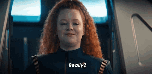 a woman with red hair is smiling and saying really ?