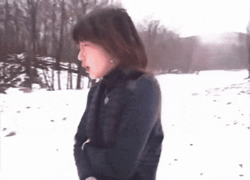 a woman in a black coat stands in the snow