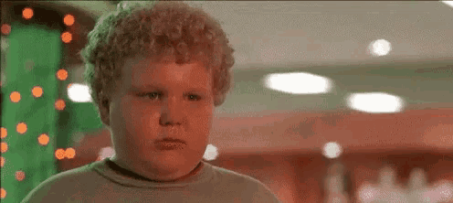 a young boy with curly hair is making a funny face .