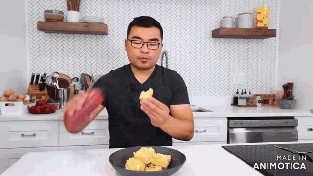 a man in a black shirt is holding a piece of food in front of a bowl of food that says made in animatica on the counter